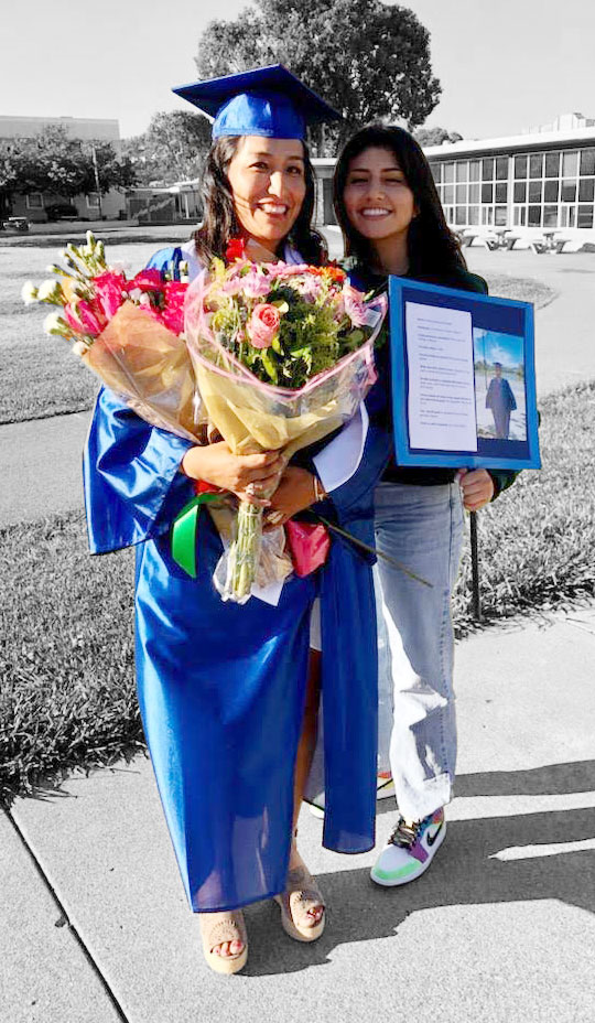 student in graduation cap and gown with flowers and mom smiling