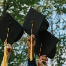 graduation cap and tassels being held up in the air